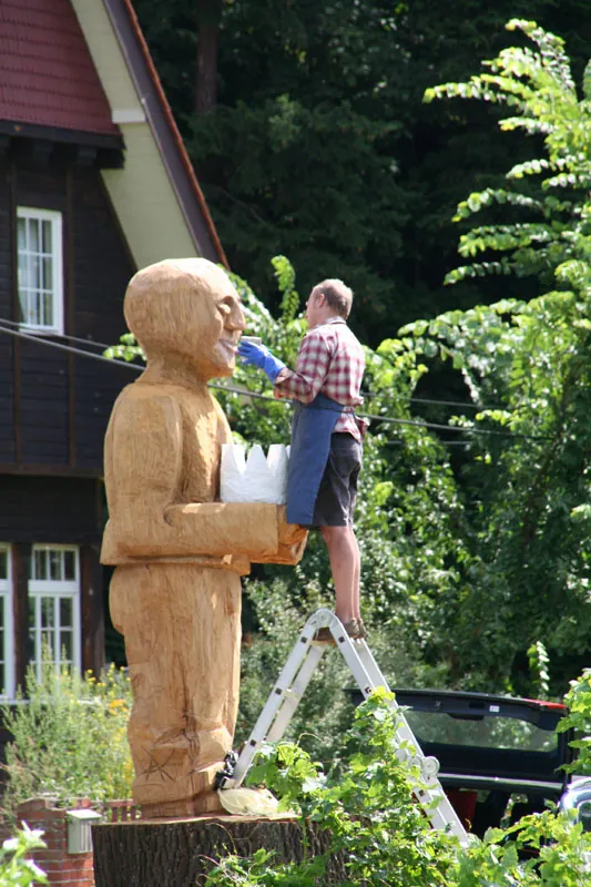 Albrecht Klink arbeitet auf einer Leiter am Kopf der fast vier Meter hohen Eichenskulptur Felix Krone in Baumgartenbrück