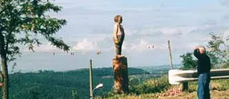 Eine etwa dreieinhalb Meter hohe Skulptur aus Zedernholz auf einem Aussichtspunkt über dem Bolsenasee