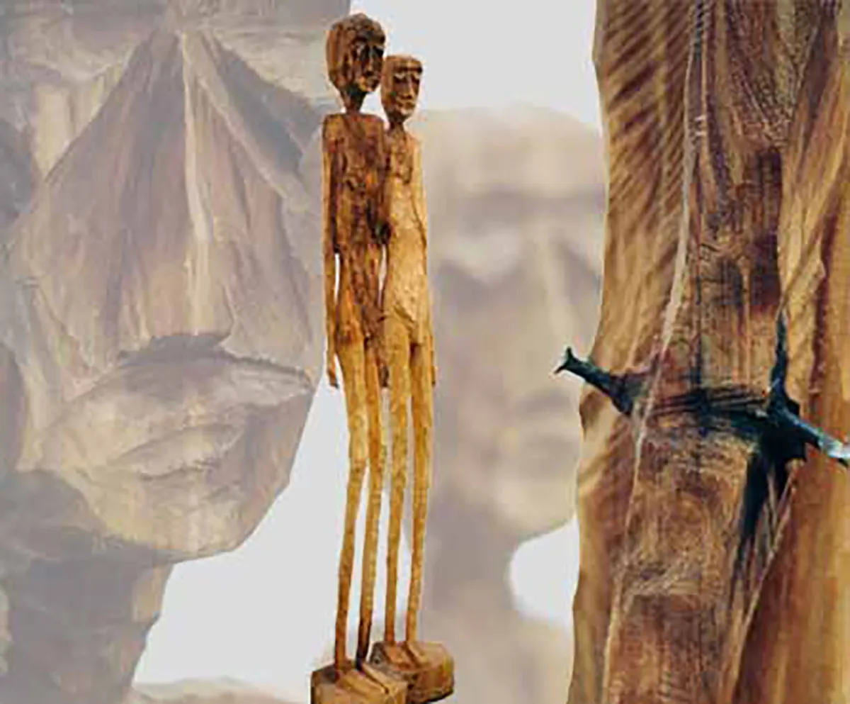 Die Doppelfigur a pierced man and the Friend aus Lindenholz, rechts daneben ein Stamm mit einem eingewachsenen alten Nagel